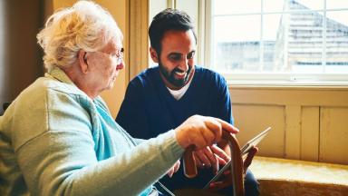 Nurse and patient looking at a tablet screen and smiling