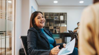 Healthcare professional sitting and smiling with paper showing a bar chart