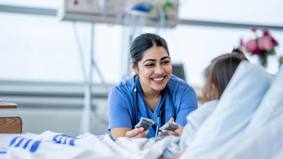 A smiling doctor talking to a patient who is in bed.