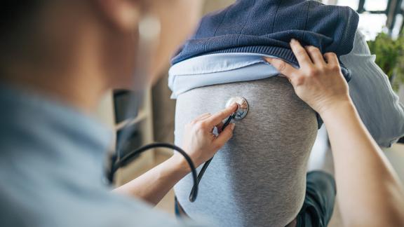 Doctor examining man's lungs with stethoscope