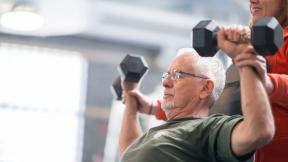 An older man lifting dumbbells.