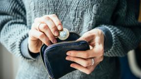 A two pound coin being put into a purse.