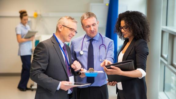 Image of three health care leaders with nurse in the background