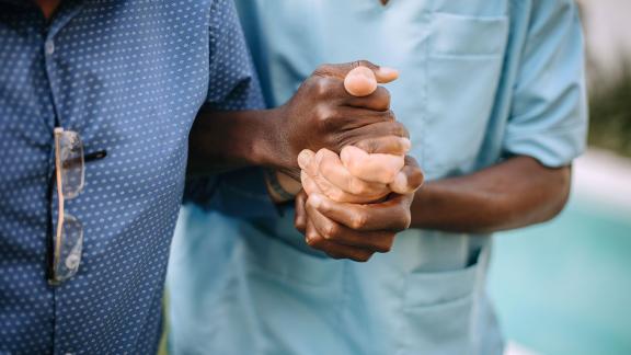 A carer supporting a patient with their arms locked together.