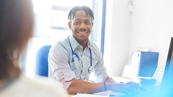 A smiling general practitioner, consulting a patient.