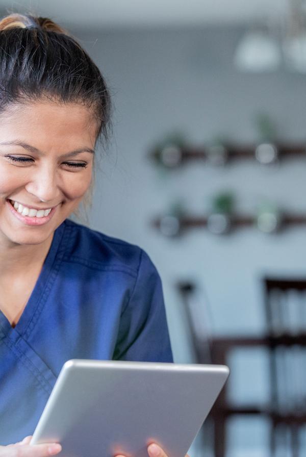 A nurse smiling at a tablet.