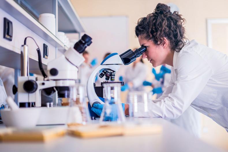 A healthcare scientist looking into a microscope.